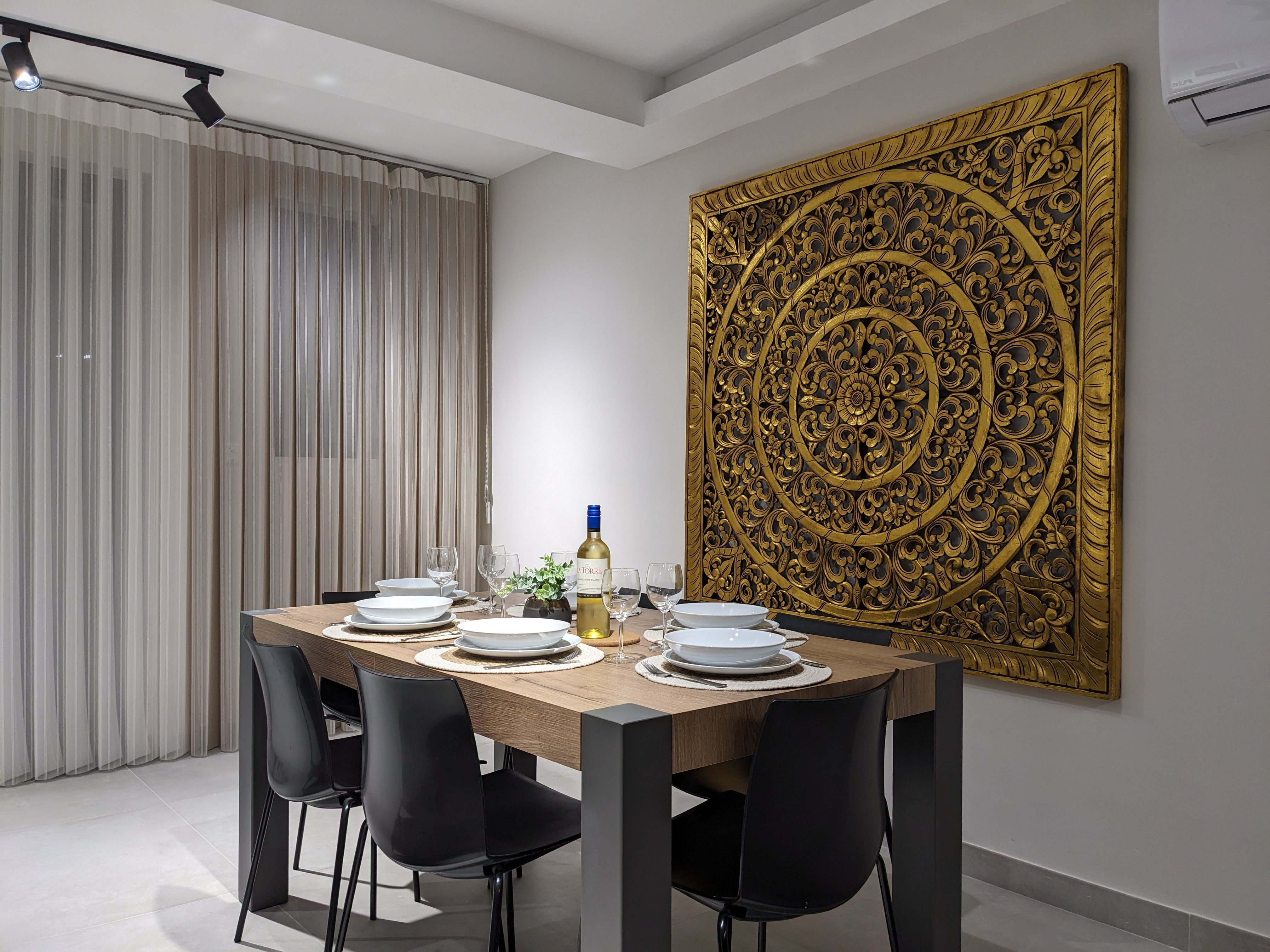 Dining table laid for six beneath a large carved gold wall panel