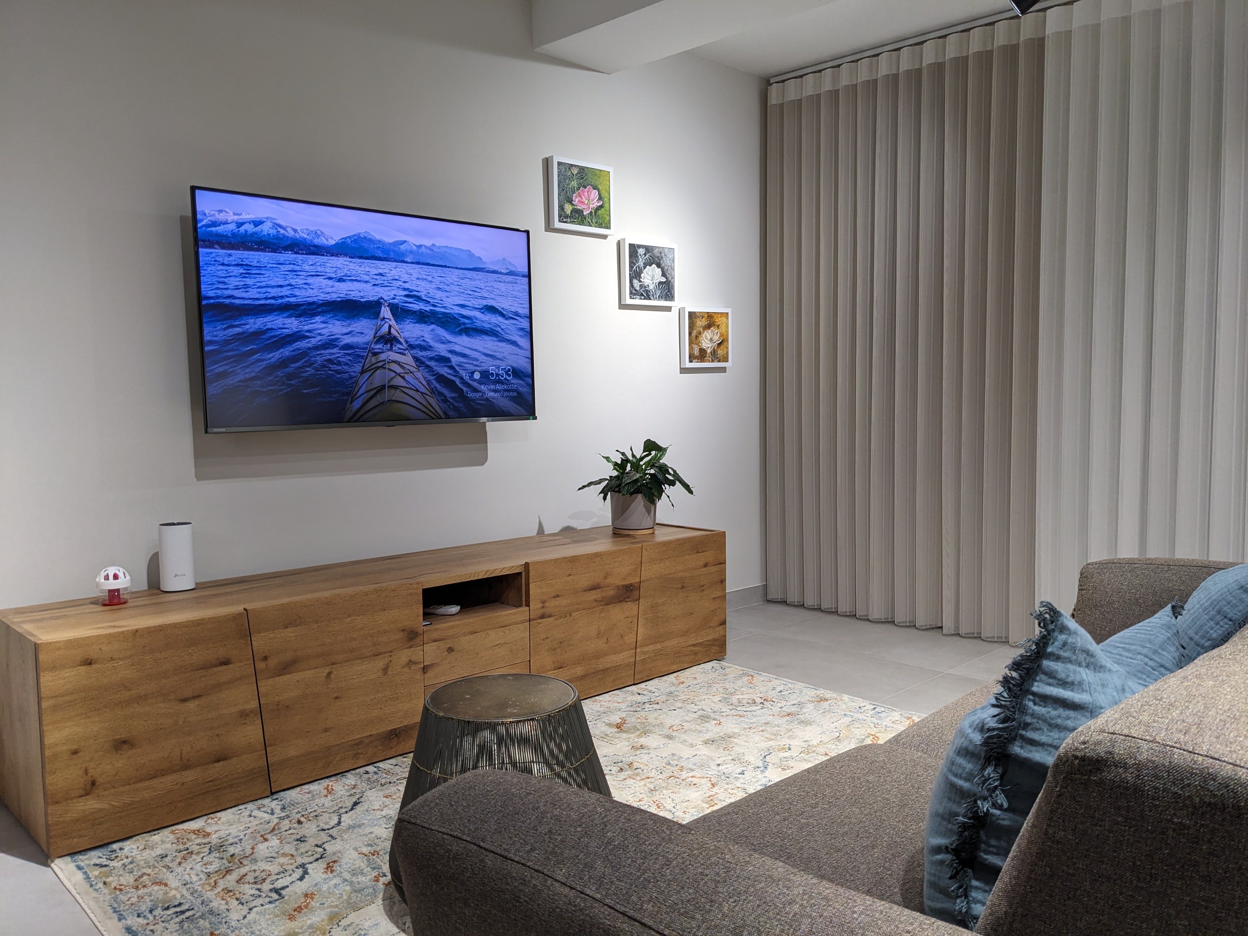 Living room with a wall-mounted television, oak sideboard and a corner sofa on a patterned rug